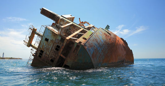 This is an image of a rusty-looking ship that has been half-tipped over and is dead in the water. Seems like the kind of place ghost pirates would love to inhabit.